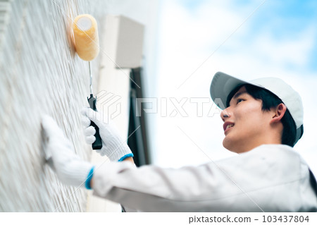 藍天下維修外牆的年輕男承包商 103437804