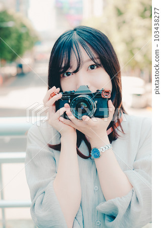 A woman holding a film camera 103438277
