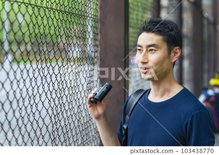 Man watching a sports game with binoculars Man watching a sports game with binoculars 103438770