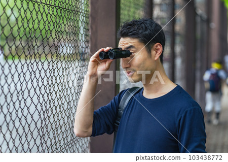 Man watching a sports game with binoculars Man watching a sports game with binoculars 103438772