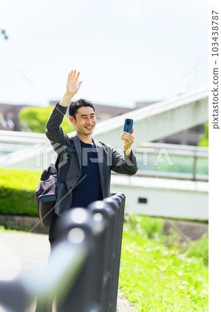 A man waving and shooting with a smartphone 103438787