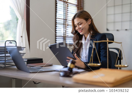 Attractive young lawyer in office Business woman and lawyers discussing contract papers with brass scale on wooden desk in office. Law, legal services, advice, Justice and real estate concept 103439232