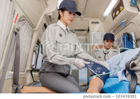 Paramedics checking blood pressure in an ambulance 103439381