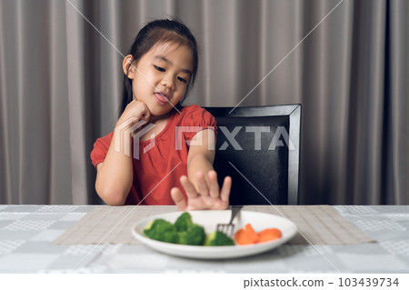 Little cute kid girl refusing to eat healthy vegetables. Children do not like to eat vegetables. Little cute kid girl refusing to eat healthy vegetables. Children do not like to eat vegetables. 103439734