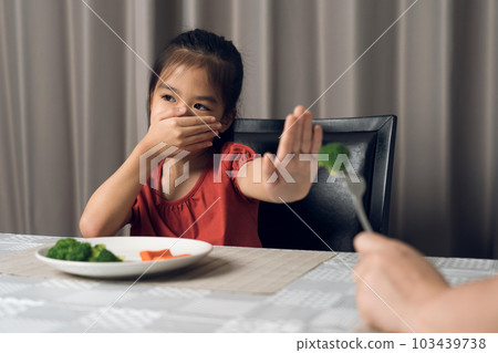 Little cute kid girl refusing to eat healthy vegetables. Children do not like to eat vegetables. 103439738