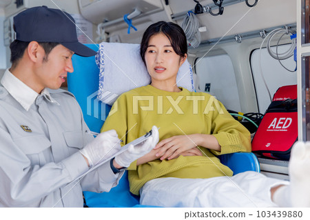 An ambulance worker asking a question to an unwell woman who called an ambulance 103439880