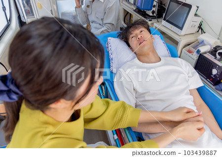 A young man being transported by an ambulance, accompanied by his wife 103439887