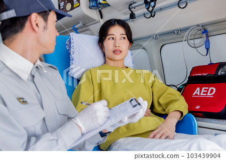 一名救護車工作人員向一名叫救護車的身體不適的婦女提問 一名救護車工作人員向一名叫救護車的身體不適的婦女提問 103439904