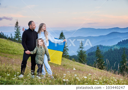 Lovely Ukrainian family resting in mountains. Male adult and his wife standing with their child. Carpathian mountains landscape. 103440247