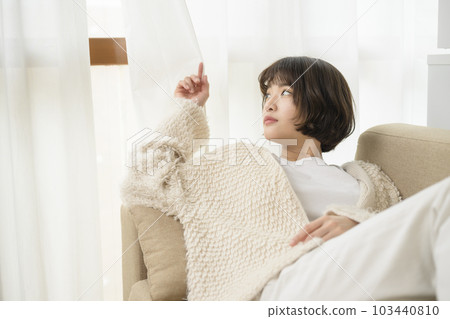Young woman looking out through the gap in the curtains 103440810