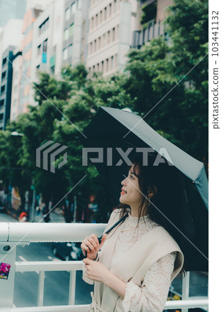 A Taiwanese woman holding an umbrella on an overpass A Taiwanese woman holding an umbrella on an overpass 103441132