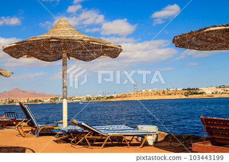 Sun umbrellas and chaise lounges on tropical beach. Concept of rest, relaxation, holidays, resort Sun umbrellas and chaise lounges on tropical beach. Concept of rest, relaxation, holidays, resort 103443199