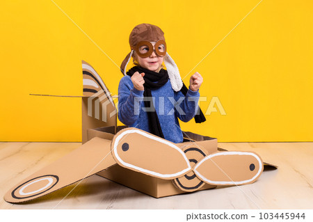 Little dreamer girl playing with a cardboard airplane. Childhood. Fantasy, imagination. 103445944