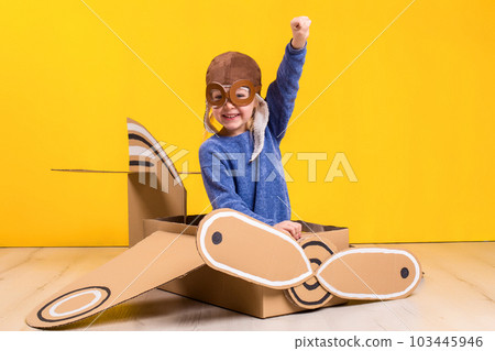 Little dreamer girl playing with a cardboard airplane. Childhood. Fantasy, imagination. 103445946