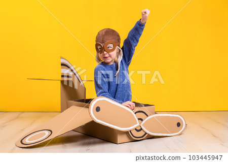 Little dreamer girl playing with a cardboard airplane. Childhood. Fantasy, imagination. Little dreamer girl playing with a cardboard airplane. Childhood. Fantasy, imagination. 103445947