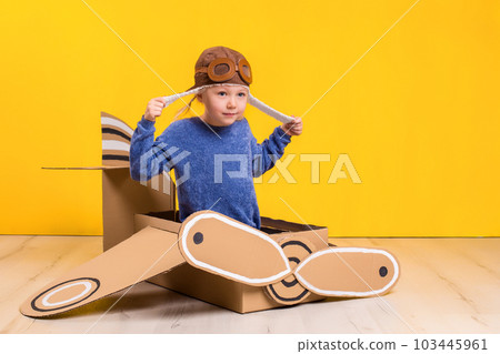 Little dreamer girl playing with a cardboard airplane. Childhood. Fantasy, imagination. 103445961