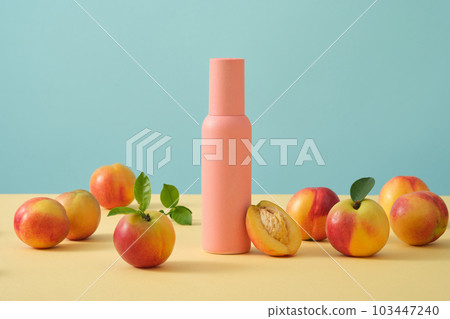 Light blue background with peaches decorated with a beauty cosmetic bottle in pink color. Peach (Prunus persica) extract helps to remove dark circles and blemishes 103447240