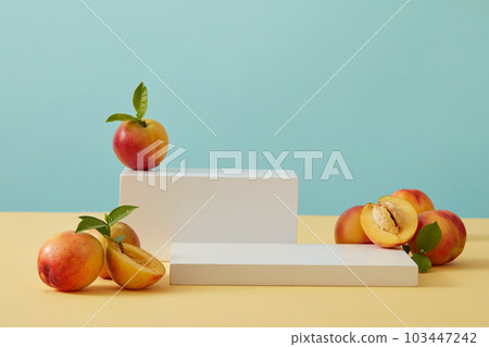 Geometric shaped podiums with some peaches are arranged. Empty area on the podium for skin care cosmetic product advertising of Peach (Prunus persica) extract 103447242