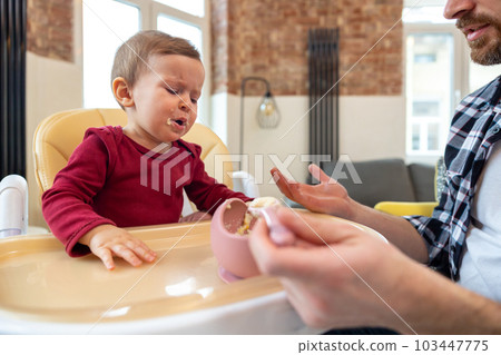 Infant little baby girl crying and don't want to eat food from her father. Infant little baby girl crying and don't want to eat food from her father. 103447775