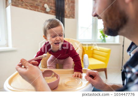 Toddler cute baby girl crying and don't want to eat food from her father. Toddler cute baby girl crying and don't want to eat food from her father. 103447776