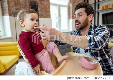 Lure first meal. Dad feeding toddler child with spoon for lunch. Lure first meal. Dad feeding toddler child with spoon for lunch. 103447785