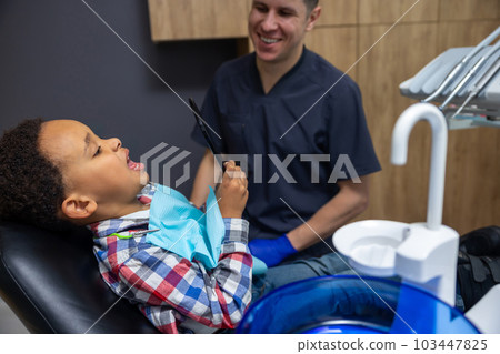 Dark-skinned boy looking at his teeth in the mirror Dark-skinned boy looking at his teeth in the mirror 103447825