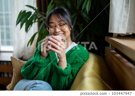 Dark-haired young girl enjoying morning tea at home Dark-haired young girl enjoying morning tea at home 103447947