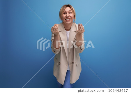 portrait of a positive blonde young woman in a cream-colored jacket with a grimace on her face on a 103448417