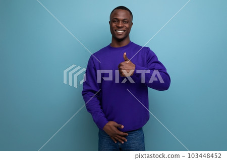 well-groomed friendly young african man in a blue sweater on a blue background with copy space well-groomed friendly young african man in a blue sweater on a blue background with copy space 103448452