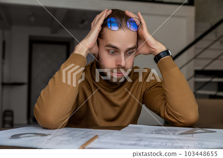Exhausted tired engineer architect working on design of house, creating blueprint, being overworked. 103448655