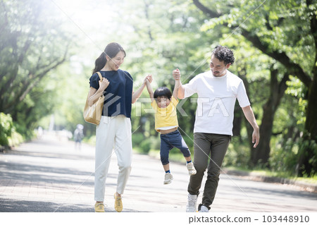 A family going out in a fresh green park or outside holding hands and going high 103448910