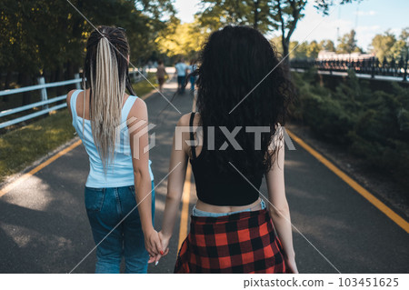 two female have friendship and walking in park holding by hands 103451625