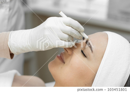 Instant lifting where woman experiences effect instant lifting, thanks to botulinum therapy, which makes her face supple and youthful. Reception with a professional cosmetologist in the beauty clinic  103451801