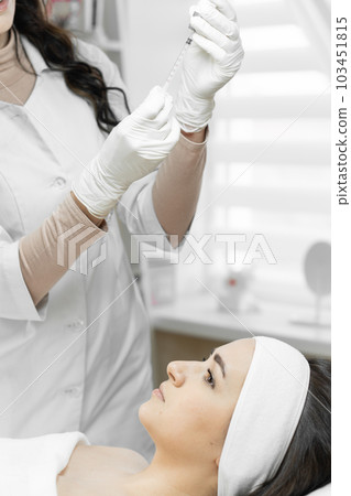 Secret of eternal youth woman discovers secret beauty by choosing botulinum therapy to maintain freshness and youthful appearance. Beautician dials syringe in beauty salon in preparation for procedure 103451815