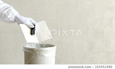 Elderly woman's hand throwing away passbook and stamp in trash can_Wide Elderly woman's hand throwing away passbook and stamp in trash can_Wide 103452480
