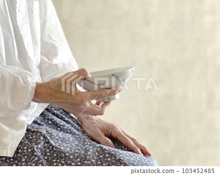 Elderly woman sitting with a bowl Elderly woman sitting with a bowl 103452485