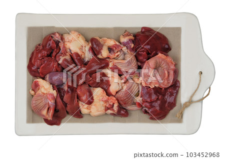 Raw chicken giblets on a ceramic board isolated on white background. Chicken stomachs, hearts and livers are prepared for cooking. Raw chicken giblets on a ceramic board isolated on white background. Chicken stomachs, hearts and livers are prepared for cooking. 103452968