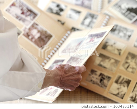 The hand of an elderly woman who opens and looks at the album 103453114