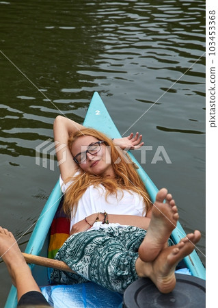 Canoeing on a river, girl relaxing on the front 103453368