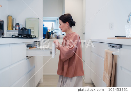 Senior woman devising storage in the kitchen Senior woman devising storage in the kitchen 103453561