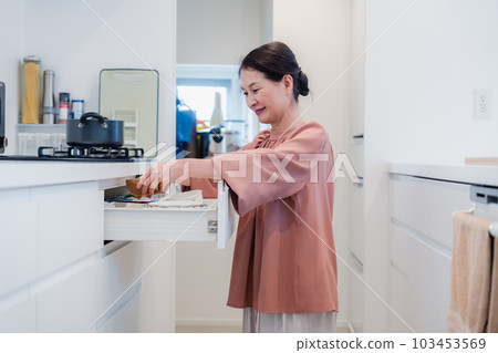 Senior woman devising storage in the kitchen Senior woman devising storage in the kitchen 103453569