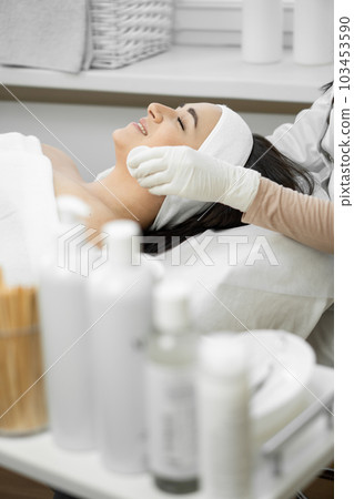 A young woman receives luxurious care from a cosmetologist who cleanses the skin, providing an individual approach and promoting rejuvenation in the beauty salon, relaxing and rest 103453590