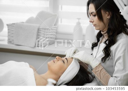 Professional care: cosmetology at a high level, when a qualified specialist cleanses the skin and provides comprehensive care for the appearance of a woman in a beauty clinic Professional care: cosmetology at a high level, when a qualified specialist cleanses the skin and provides comprehensive care for the appearance of a woman in a beauty clinic 103453595
