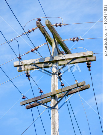 Electric pole and wires, wood electricty pole on blue sky background. 103454032