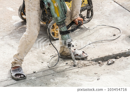 Construction worker using jackhammer drilling concrete surface 103454716