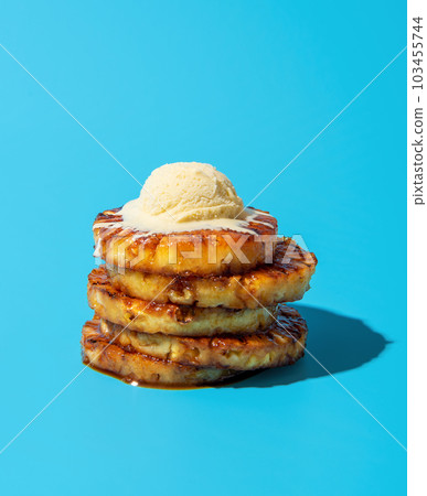 Summer dessert, grilled pineapple with vanilla ice cream, isolated on a blue background Summer dessert, grilled pineapple with vanilla ice cream, isolated on a blue background 103455744