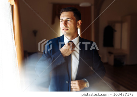 Stylish groomsmen. Businessman. Luxury man in suit in room. Groom morning preparation. Wedding day. Stylish groomsmen. Businessman. Luxury man in suit in room. Groom morning preparation. Wedding day. 103457172