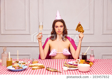 Beautiful young girl with bright makeup, sitting at table, celebrating her birthday, eating chicken and drinking champagne 103457832