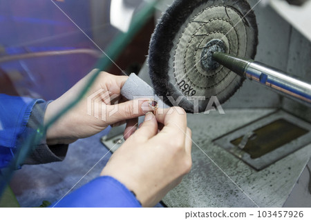 Jewelry industry. Hands make a golden decoration. Grinds the ring. 103457926