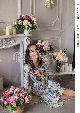 Beautiful young woman sitting in a room among the flowers 103458625
